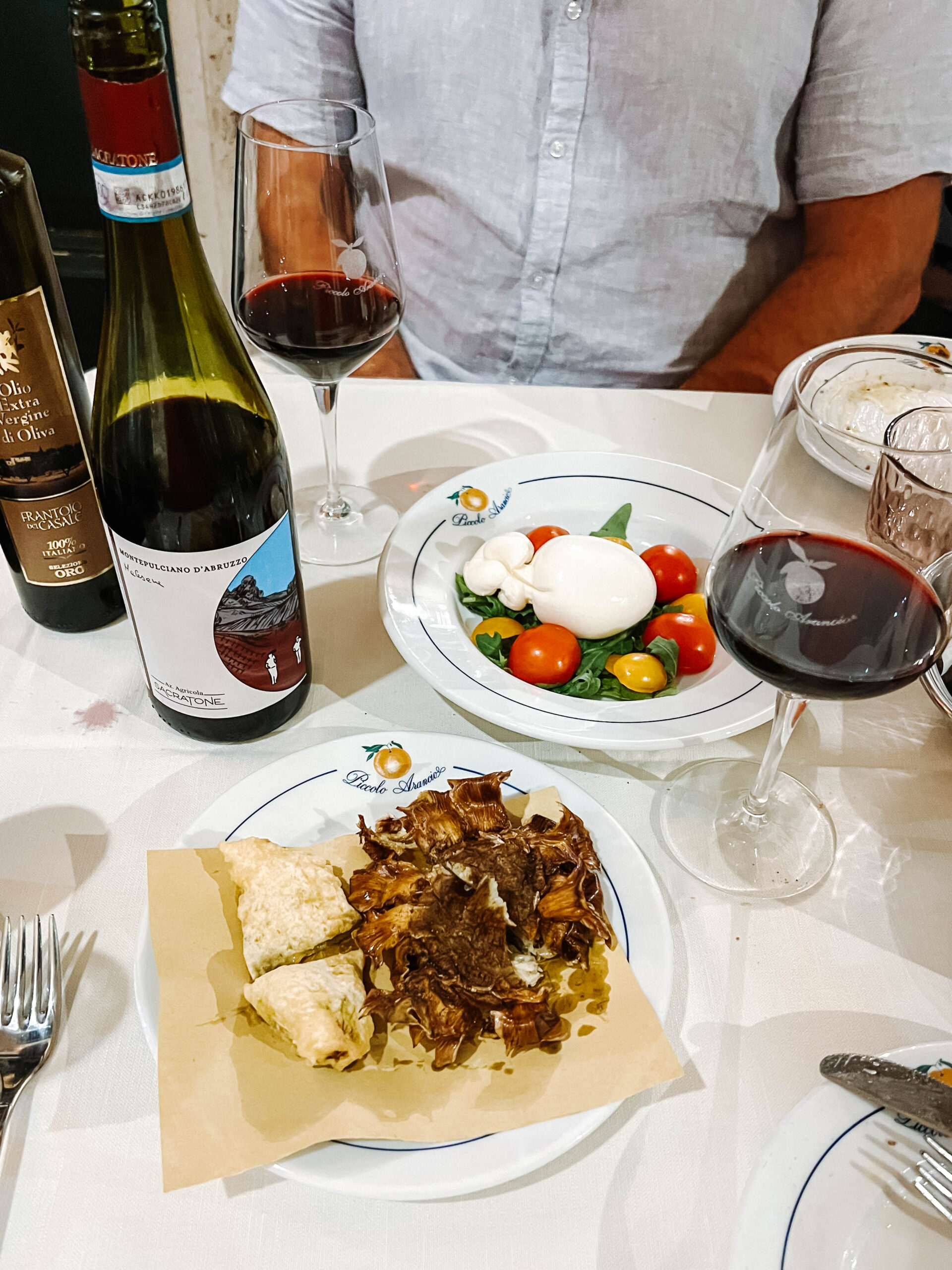 Looking down at a table with fried artichoke and caprese salad at Piccolo Arancio in Rome