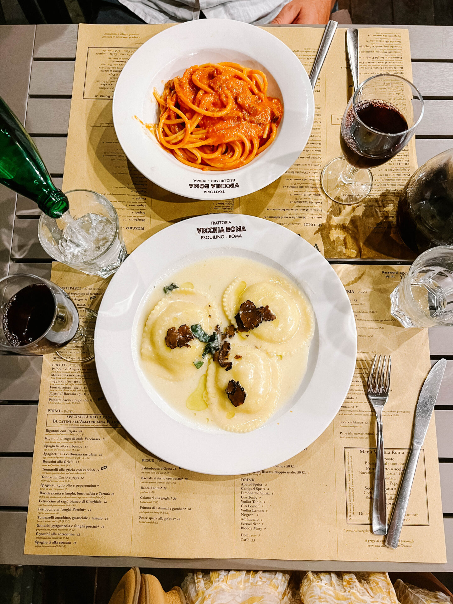 Looking down at a table with two plates of pasta, wine and water at Trattoria Vecchia Roma