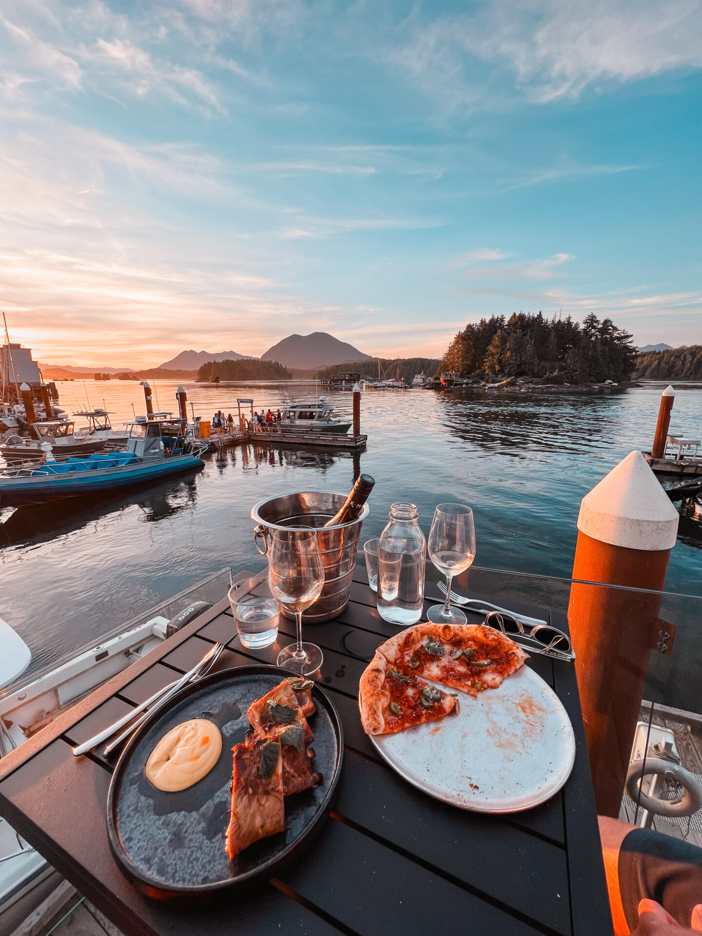 Sunset of the Tofino inlet with dinner and a bottle of wine on a table at Shelter Restaurant 